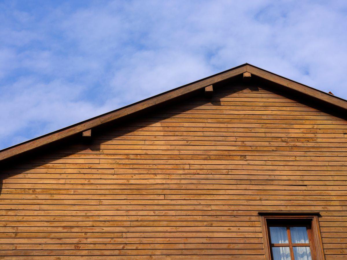 The gable end of a house clad in horizontal timber boards, with a window at the lower right corner.
